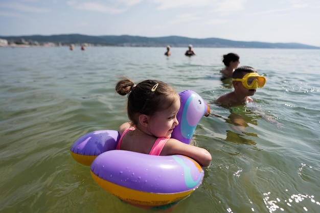 As crianças nadam no mar em um anel inflável no verão