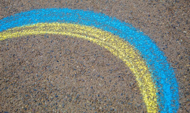 As crianças pintam um arco-íris no asfalto Foco seletivo