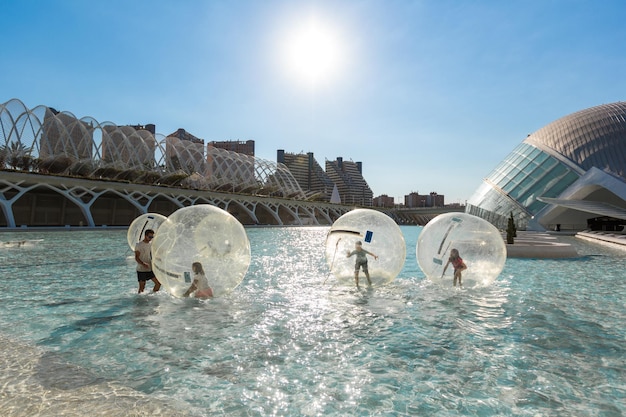 As crianças se divertem dentro de grandes balões de ar em uma piscina na cidade das artes e ciências em Valência, Espanha