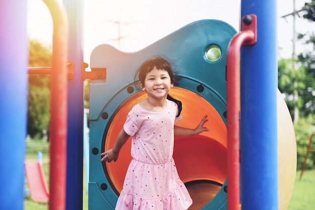 As crianças sorriem se divertindo menina brincando fora feliz no parque jardim sentado no playground, dia internacional da criança crianças asiáticas bonito bonito