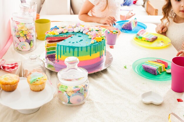 As criancinhas comendo bolo colorido e outros doces na festa de aniversário