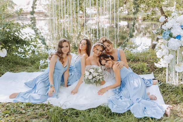 As damas de honor estão de vestidos azuis a noiva está segurando um belo buquê sentada desfrutando da celebração belo conceito de blog de casamento de luxo casamento de primavera