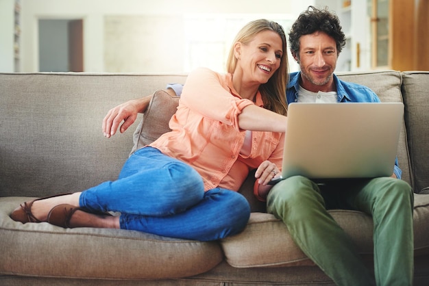 As datas do filme no sofá são a melhor foto de um casal maduro feliz usando um laptop juntos no sofá em casa
