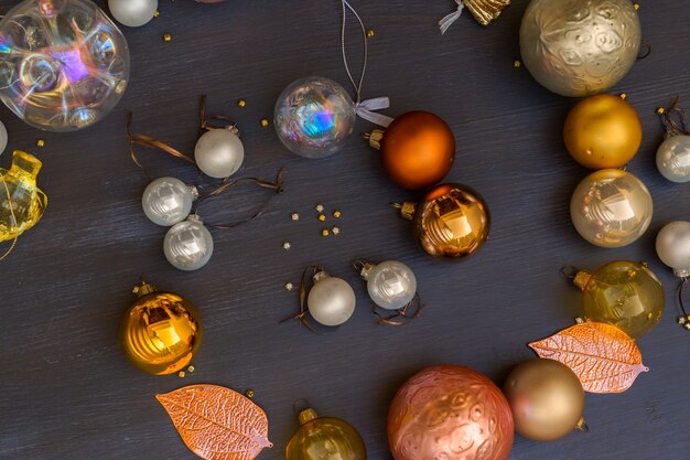 As decorações de Natal douradas e prateadas espiralam sobre um fundo escuro de madeira, moldura com espaço de cópia