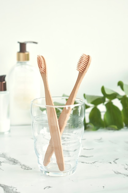 As escovas de dente de bambu são ecológicas em um copo com uma cópia do espaço em um fundo branco-mármore. Desperdício Zero. Plástico grátis.