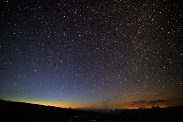 As estrelas brilhantes da via láctea no céu noturno acima do horizonte antes do amanhecer.