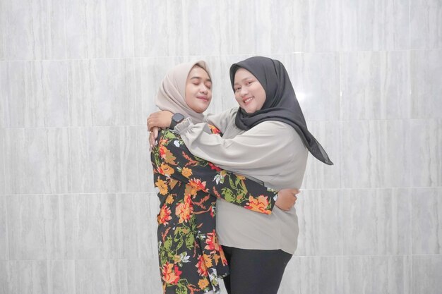 As expressões sorridente de duas mulheres indonésias vestindo hijabs vestindo roupas florais e brancas