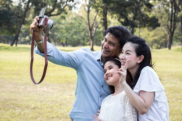 As famílias asiáticas estão tirando fotos de família em um parque público.