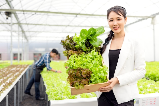 As hortaliças frescas são colhidas por agricultoras asiáticas em fazendas com sistema de plantas hidropônicas na estufa e vendidas. vegetais frescos e o conceito de comida saudável.