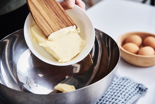 Foto as mãos colocam uma manteiga na tigela. receita culinária