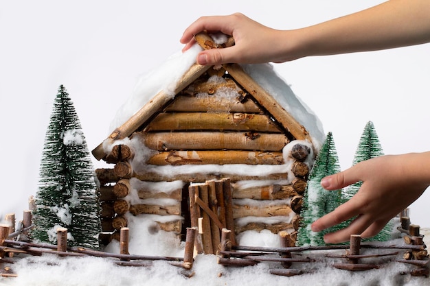 As mãos da criança seguram uma casa de madeira em miniatura