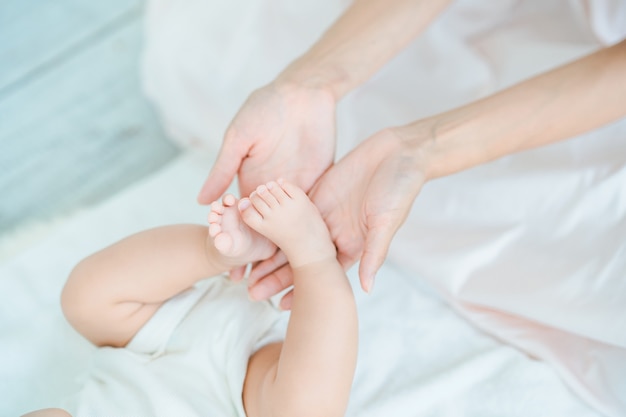 As mãos da mãe apoiando os pés do bebê no quarto