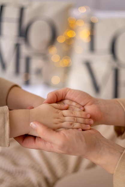 As mãos da mãe seguram as mãos de uma criança pequena os dedos do bebê estão fechados em foco marrom e bege tingindo o conceito de família e amor