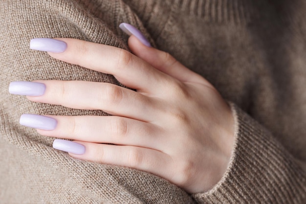 As mãos da menina com uma manicure roxa suave