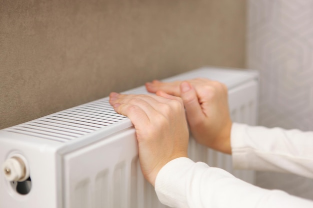 As mãos da menina verificam o radiador para o calor