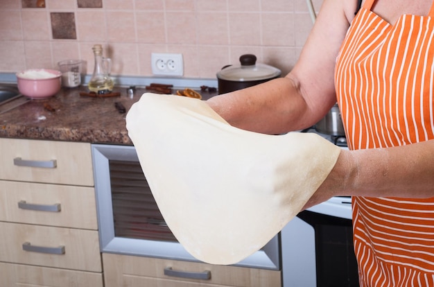 As mãos da mulher amassam a massa Cozinhando a pizza