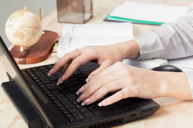 As mãos da mulher estão digitando no teclado do laptop