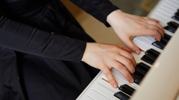 As mãos da mulher no teclado do piano closeup