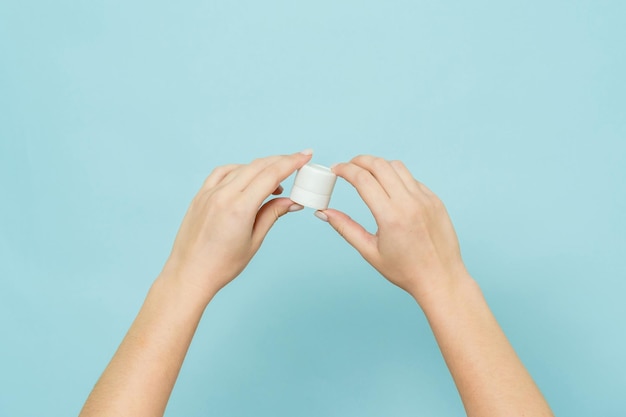 As mãos da mulher seguram um frasco de creme ou pomada Embalagem de produto cosmético