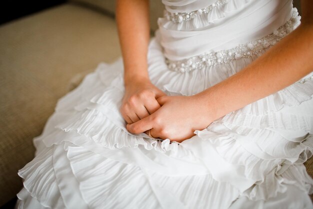 As mãos da noiva no fundo de um vestido de noiva branco