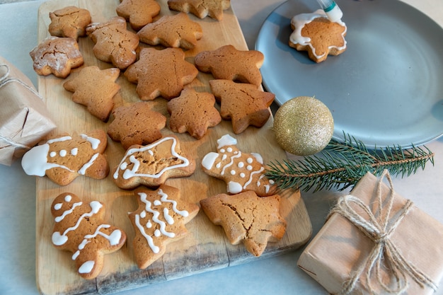 As mãos das crianças fazem biscoitos de gengibre de ano novo em uma mesa de madeira. Fazendo biscoitos com um cortador de biscoitos. Conceito de ano novo e Natal.