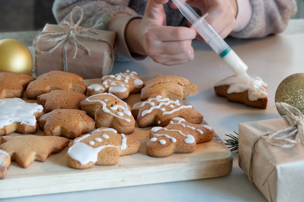 As mãos das crianças fazem biscoitos de gengibre de ano novo em uma mesa de madeira. Fazendo biscoitos com um cortador de biscoitos. Conceito de ano novo e Natal.