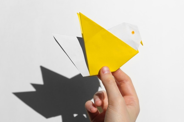 Foto as mãos das crianças fazem origami de papel colorido sobre fundo branco. papel de origami. faça você mesmo.