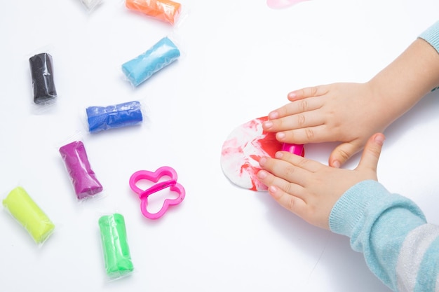 As mãos das crianças jogam massa para a criatividade das crianças. Jogo de tabuleiro para o desenvolvimento de habilidades motoras finas