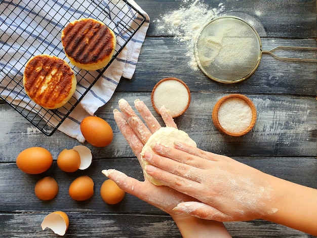 As mãos das meninas formam bolos de queijo para assar