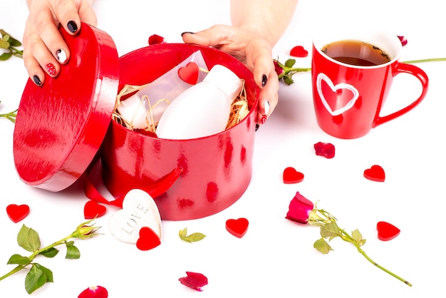 As mãos das mulheres abrem uma caixa de presentes com produtos cosméticos Presente para uma mulher Feliz dia da mulher