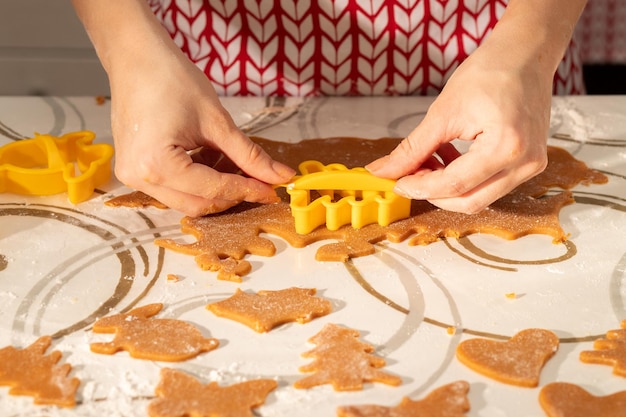 As mãos das mulheres cortam formas para biscoitos