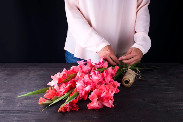 As mãos das mulheres criam um buquê de flores de gladíolo