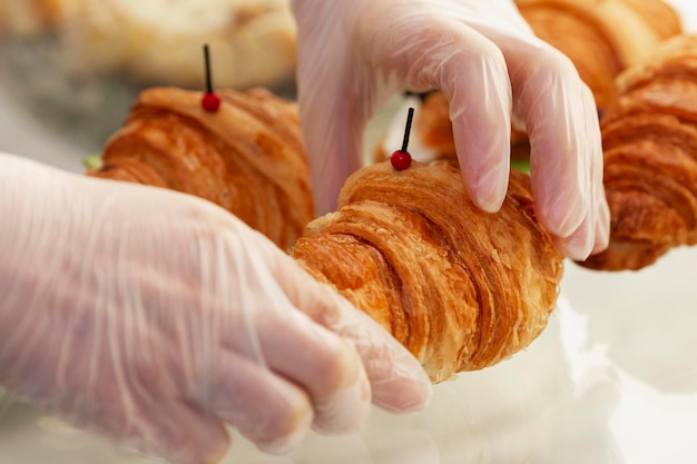 As mãos das mulheres em luvas seguram um croissant Listagem de produtos à venda Reuniões de negócios e coffee breaks Closeup