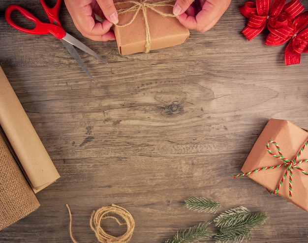 As mãos das mulheres embrulham caixas de presente de Natal com ferramentas de embrulho