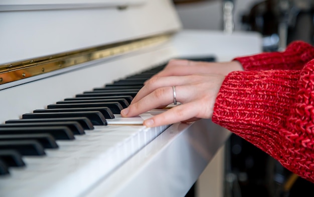 As mãos das mulheres tocam em um piano branco closeup