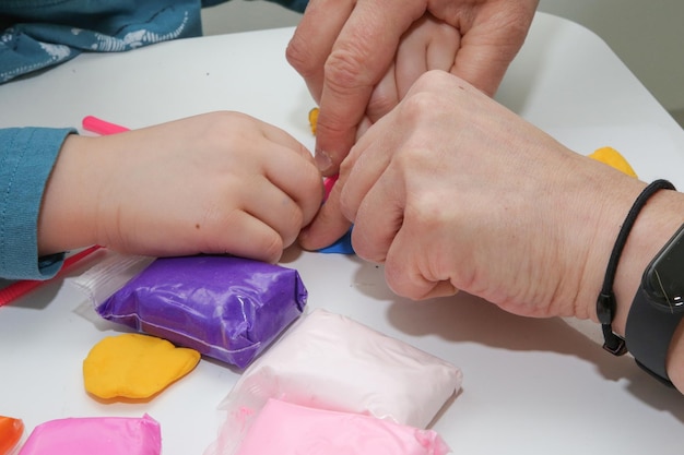 as mãos de crianças e adultos são moldadas juntas a partir de plasticina