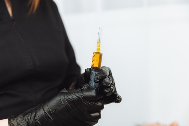 As mãos de um cosmetologista coletam plasma em uma seringa para injeção de plasmolifting