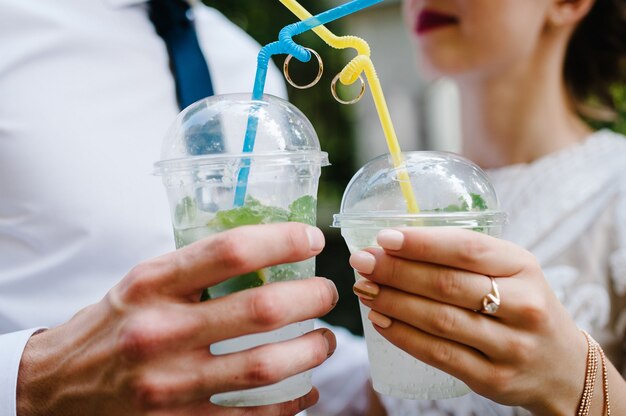 As mãos de um homem e uma mulher seguram copos de plástico com vinho