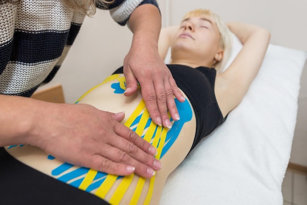 Foto as mãos de uma fisioterapeuta feminina aplicam fita adesiva terapêutica elástica à fêmea