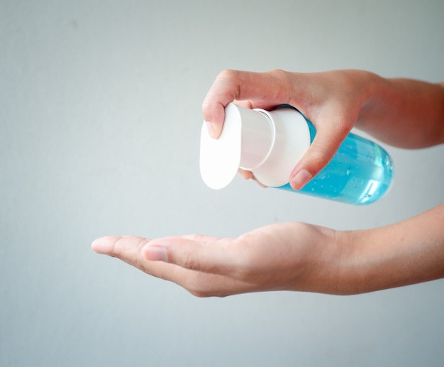 As mãos de uma mulher estão lavando as mãos com gel de álcool para matar o Coronavírus