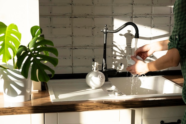 Foto as mãos de uma mulher lavam os pratos em casa pratos sob um riacho de água na luz do sol rotina doméstica
