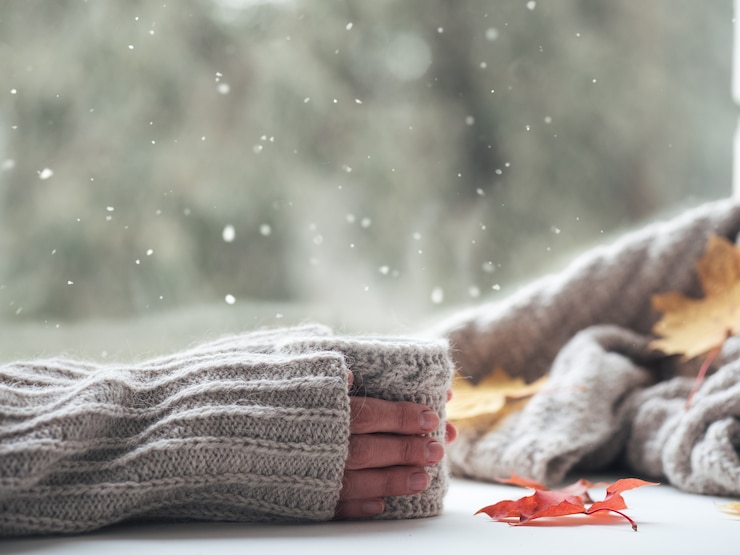 Foto as mãos de uma mulher seguram uma xícara de chá ou café quente na janela
