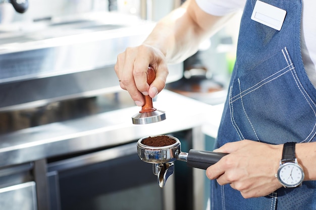As mãos do barista temperam o café no contexto de uma máquina de café