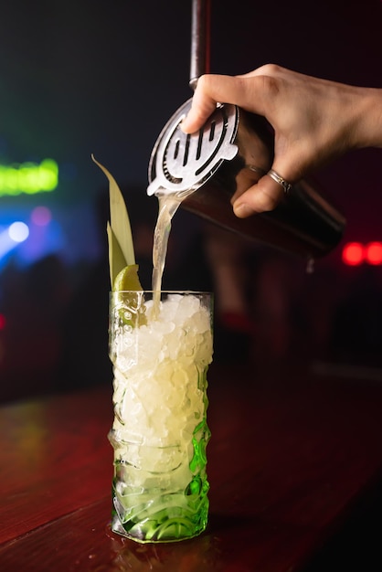 As mãos do barman 39s derramam suco em um copo de coquetel cheio de bebida alcoólica e gelo em um pub de restaurante Refrigerante alcoólico em uma boate
