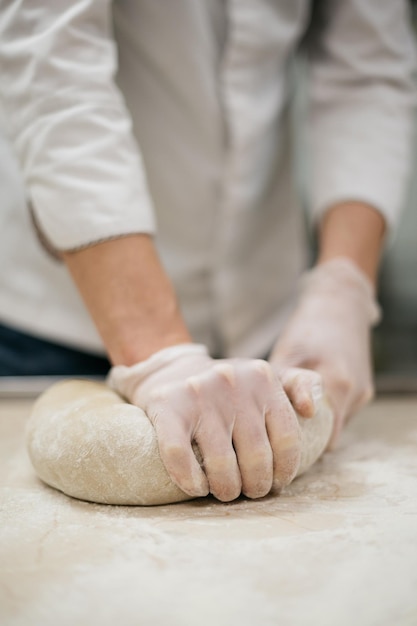 as mãos do chef masculino amassam a massa para assar pão. Foto de alta qualidade