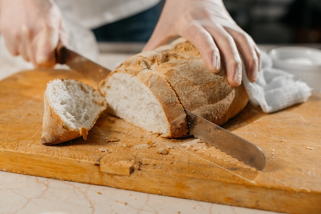 As mãos do chef masculino cortam o pão. Foto de alta qualidade