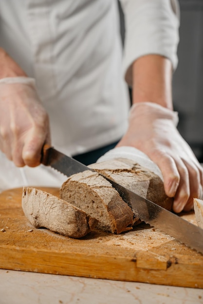 As mãos do chef masculino cortam o pão. Foto de alta qualidade