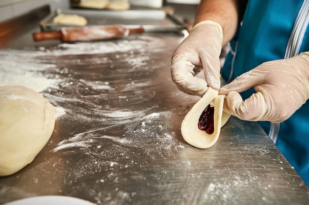 As mãos do chef prepara tortas de cereja na cozinha do restaurante. o processo de fazer pães doces. massa crua para assar no forno.