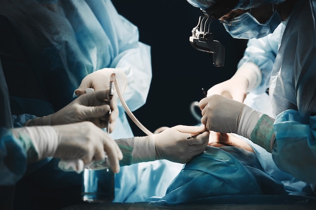 As mãos do cirurgião estão segurando uma ferramenta operacional na sala de cirurgia