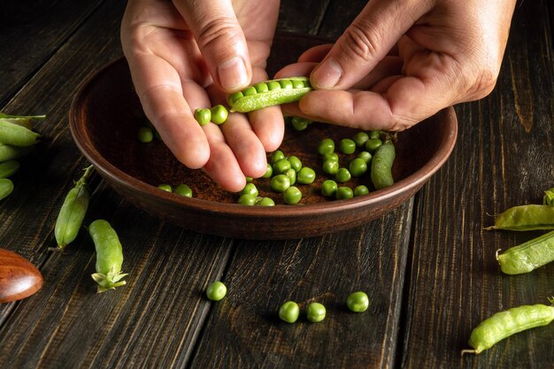 As mãos do cozinheiro separam as ervilhas das vagens verdes